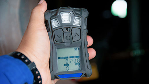 Hand holding a portable gas detector.