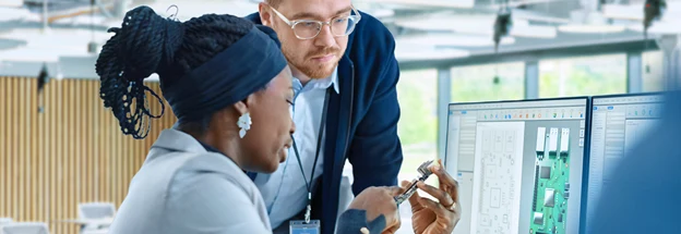 Engineer talks with colleague while holding a circuit board