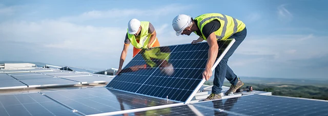 Construction workers installing a solar panel on a rooftop.