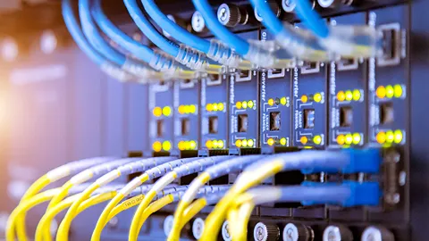 Network switch with blue and yellow ethernet cables, active lights.