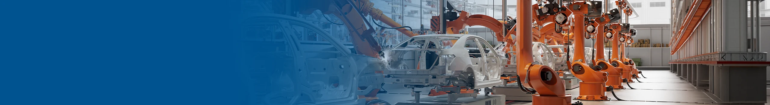 Orange robots welding car frames on an assembly line.