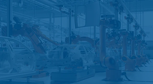 Orange robots welding car frames on an assembly line.