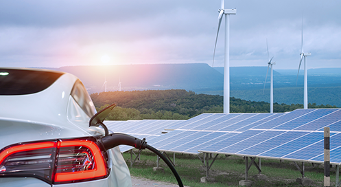 Hydrogen-powered zero‑emission car refueling at an H₂ station with wind turbines and solar panels in the background.