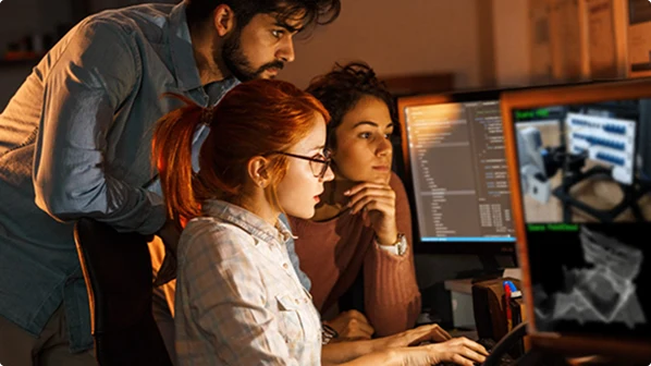 Three programmers collaborating on code at night.