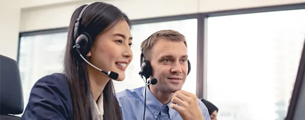 Two smiling call center agents wearing headsets.