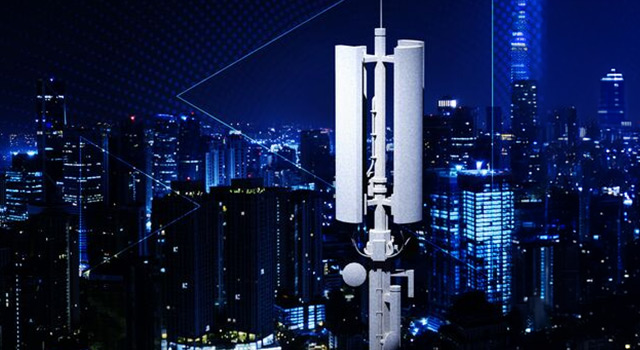 A rooftop cellular antenna overlooking a brightly lit city skyline at night.