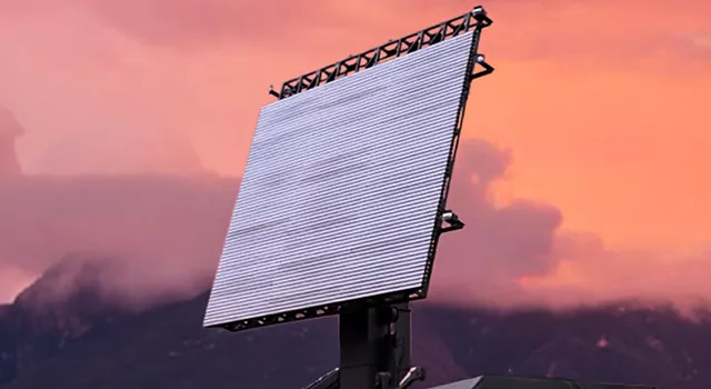 Phased array radar against a vibrant sunset sky with mountains.