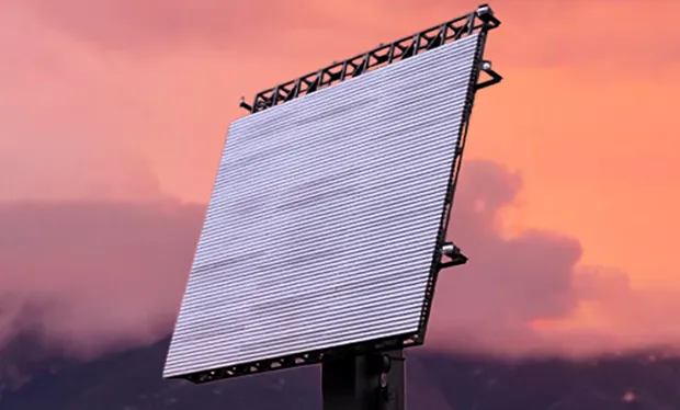 Phased array radar against a vibrant sunset sky with mountains.