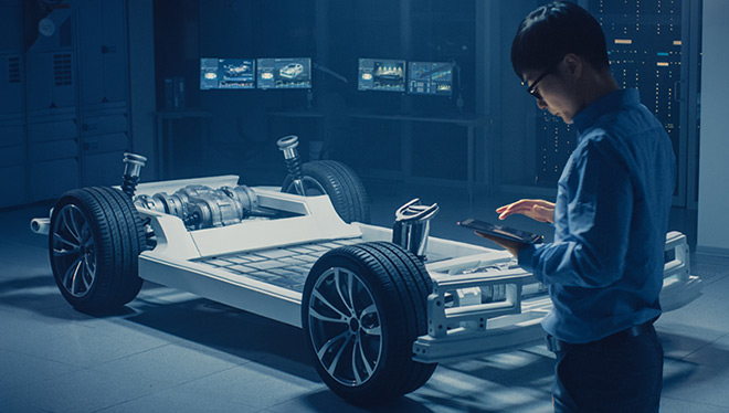 Engineer with tablet inspects EV chassis in a lab.