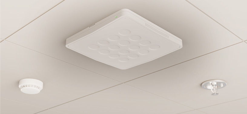 Ceiling-mounted small cell radio device, with adjacent smoke detector and sprinkler, demonstrating indoor communication and safety systems.
