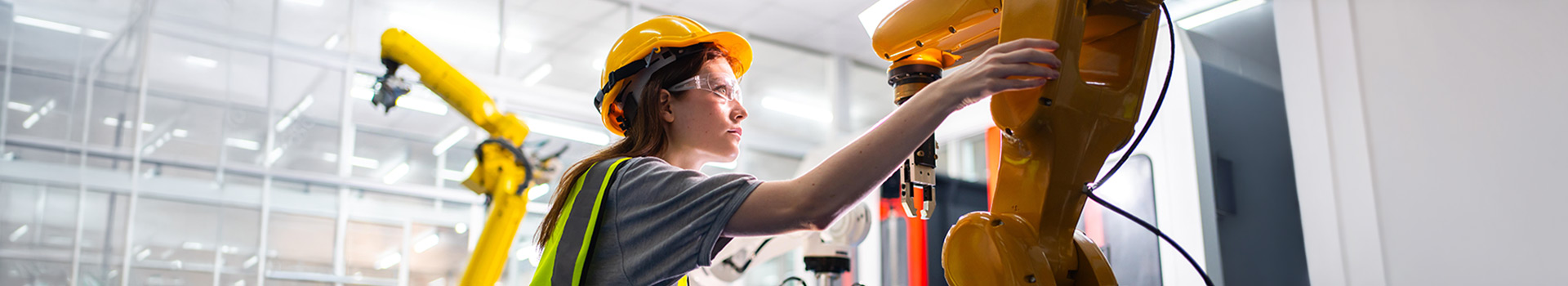 Engineer in hard hat and safety glasses working with robot.