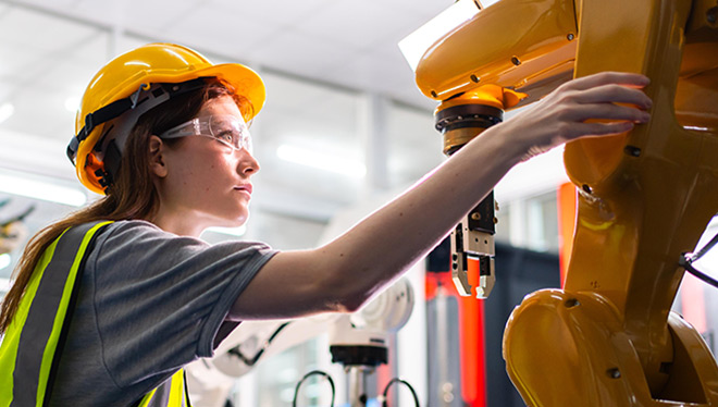 Engineer in hard hat and safety glasses working with robot.