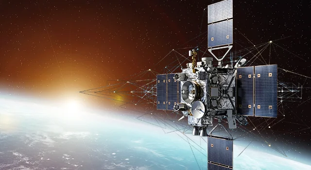 Satellite with solar panels in orbit above Earth at dawn.