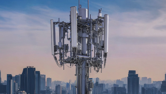 Large cellular base station tower with multiple antennas against a city skyline, representing 5G network deployment.