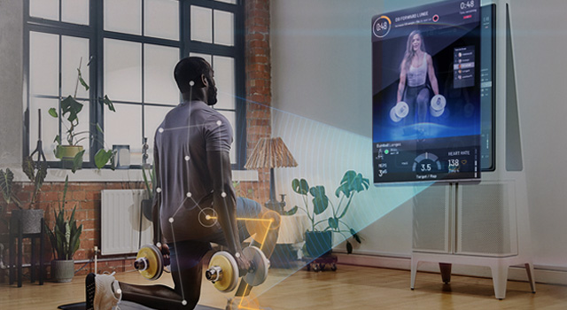 Adult male lunging with dumbbell weights. Exercising in front of a Tempo Studio 'smart' home gym system.