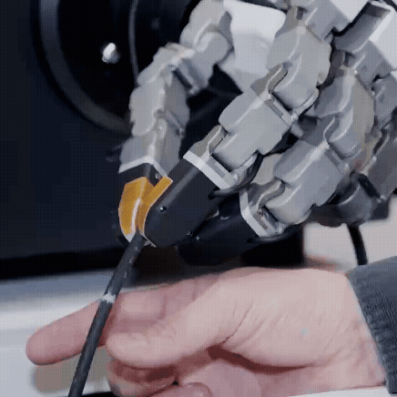 a robotic hand maintaining its grip on a small white rope that a human hand is pulling on. 