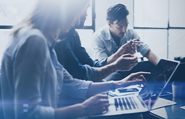 Group of professionals collaborating around a laptop in a bright office space.