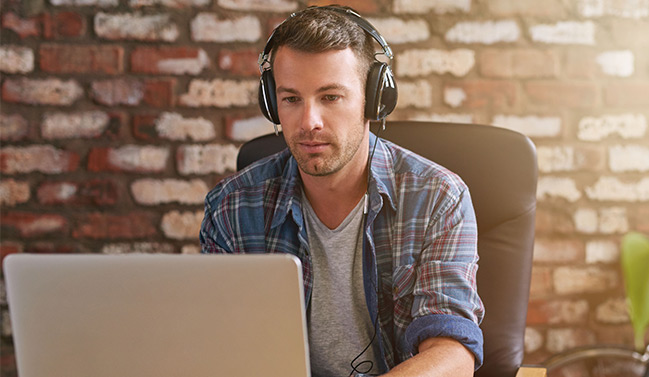 Young male employee working with headphones