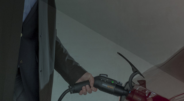 Man in parking garage charging an electric vehicle