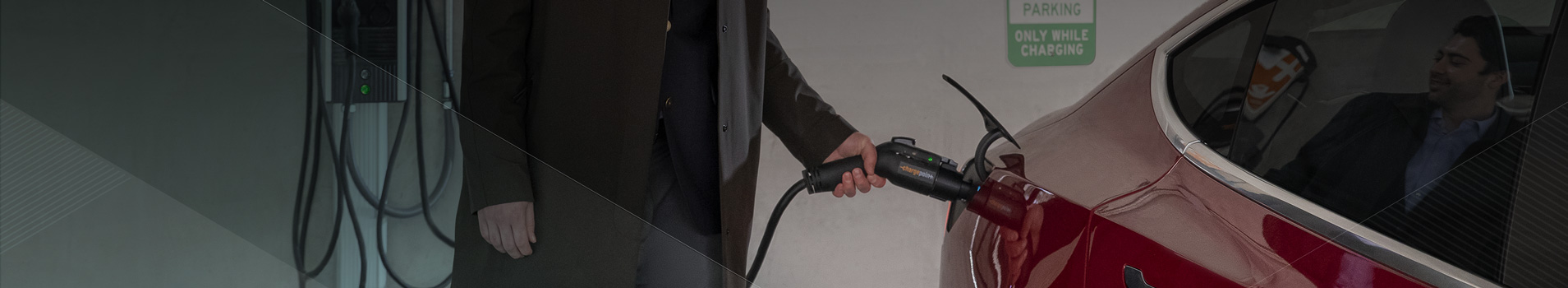 Man in parking garage charging an electric vehicle