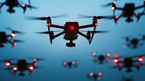Group of drones with red lights flying in formation, main drone in focus.