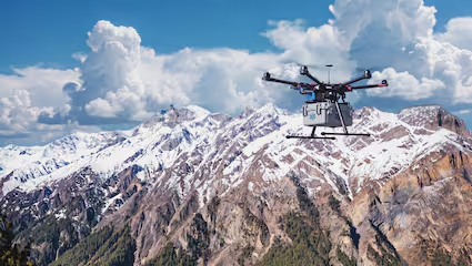 Helicopter flying over snow covered mountains.