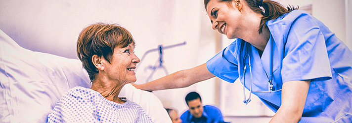 A woman in a hospital bed being assisted by a nurse