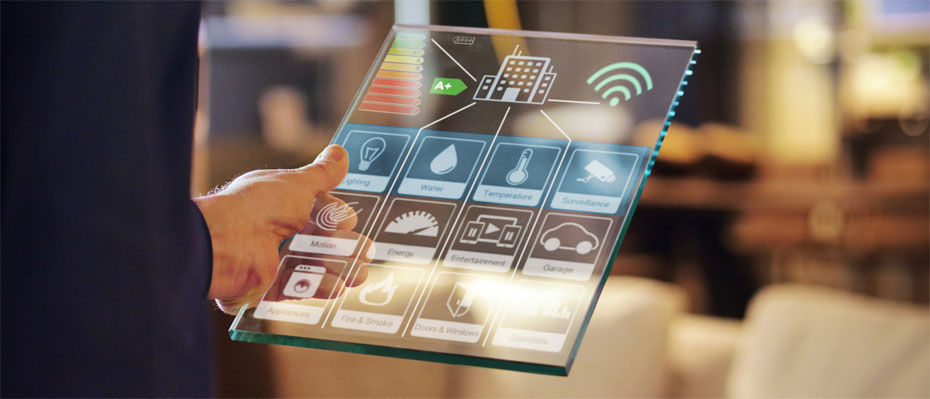 A person holds a transparent tablet displaying a smart building interface with various control icons.
