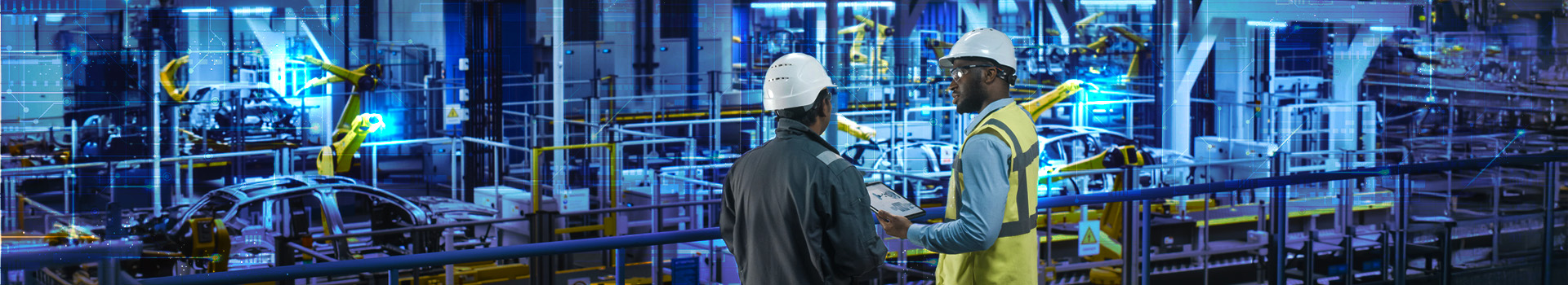 An image of a factory car assembly line with factory workers reviewing documents