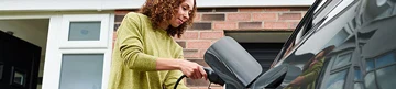 Woman charging electric vehicle at a charging station. Woman charging electric vehicle at a charging station.
