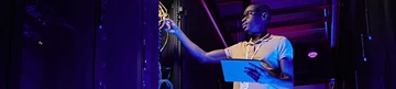 Man inspecting cables in a server rack. Man inspecting cables in a server rack.