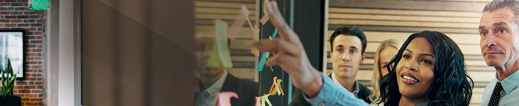 Woman working with coworkers placing stickies on glass wall