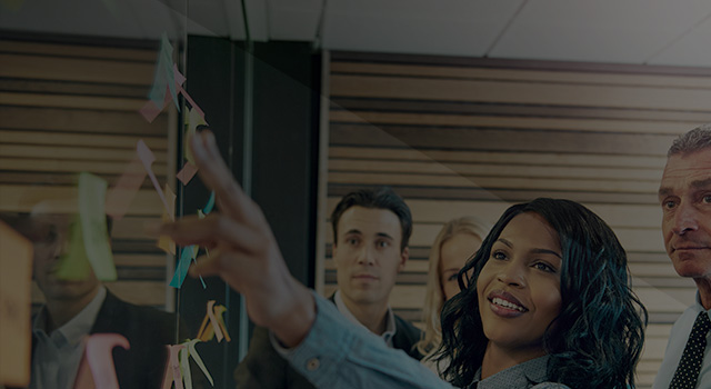 Woman working with coworkers placing stickies on glass wall