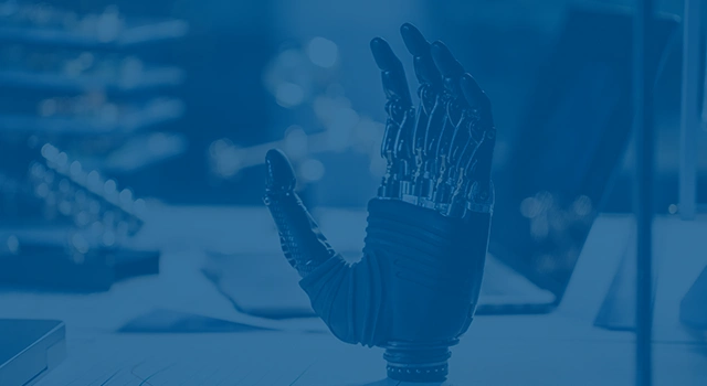 Close-up of a robotic hand on a desk with technical drawings.
