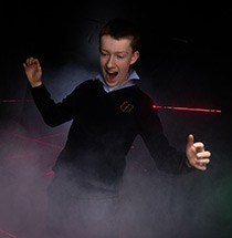 Excited child navigating through a laser vault challenge at an Analog Devices event.