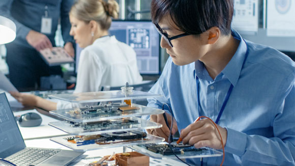Engineer works with robot, soldering wires and circuits