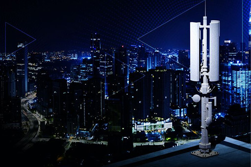 A rooftop cellular antenna overlooking a brightly lit city skyline at night.