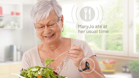 Senior woman eating salad triggers an alert on the Tempo watch that she is having a meal.