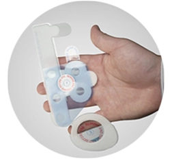 Hand holding transparent medical device with circular adhesive pads, designed for attaching sensors.