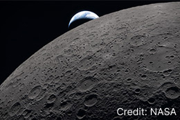 The lunar surface while a distant Earth sets in the background