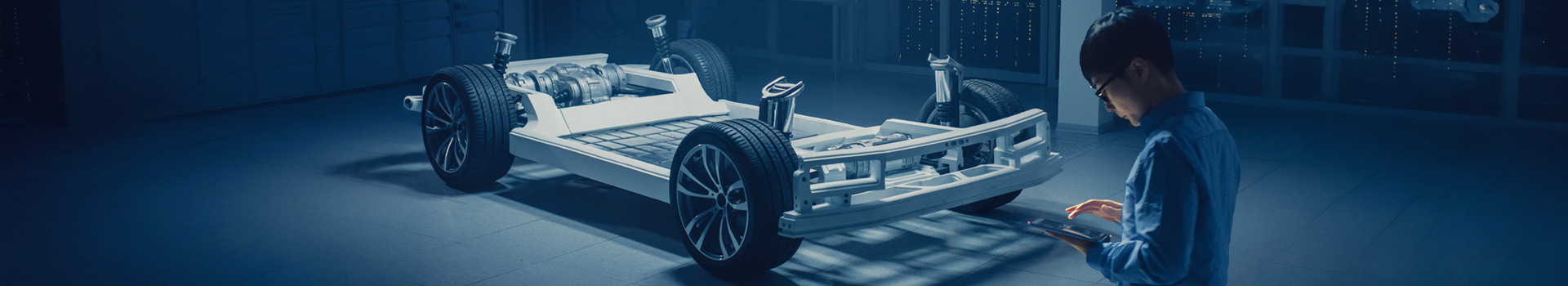 Engineer with tablet inspects EV chassis in a lab.