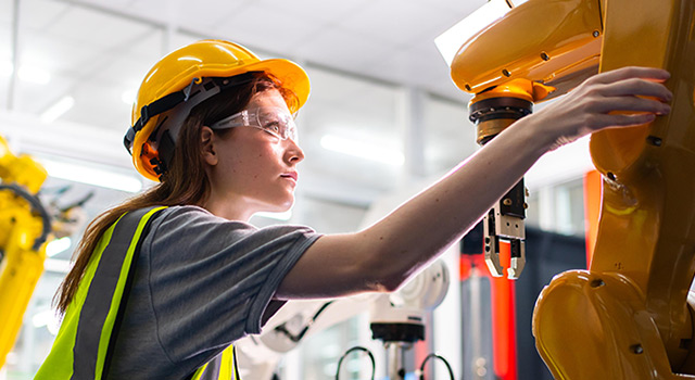 Engineer in hard hat and safety glasses working with robot.