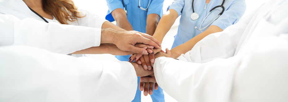 Close up image of medical staff joining stacked hands; showing unity – emphasizing value-based care.