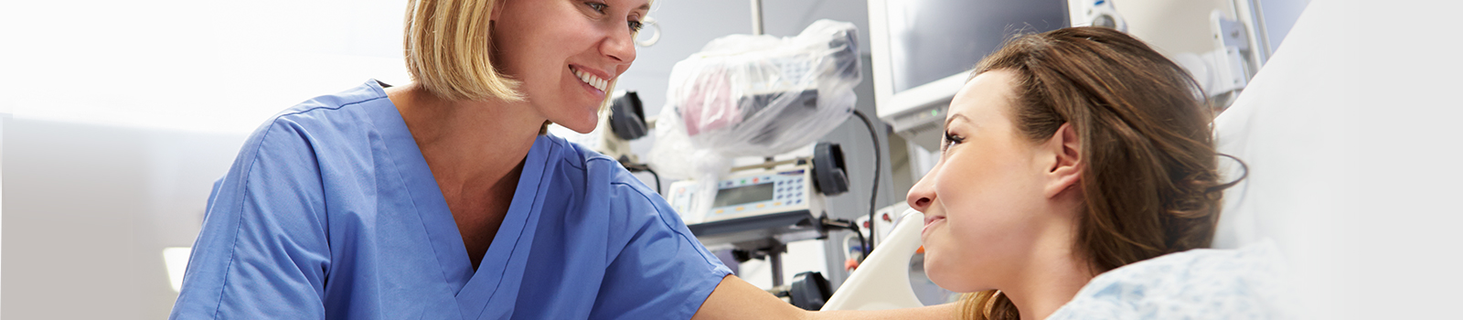Close-up of female nurse caring for female patient in hospital room.