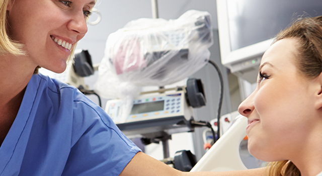 Close-up of female nurse caring for female patient in hospital room.