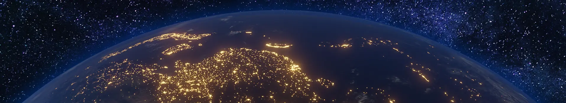 View of Earth from space at night, showing illuminated city lights across Europe and surrounding regions, with a star-filled sky in the background.