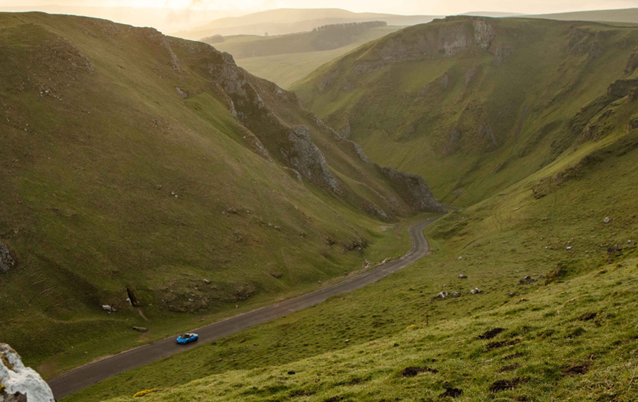 Lotus car driving on road through a scenic mountain environment