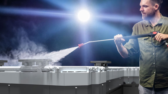 Man using a power washer to spray-clean MagneMover tracks and carts.