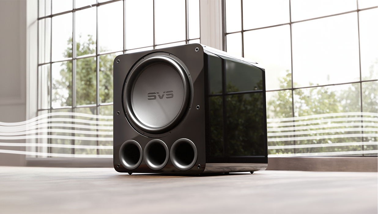 A close-up shot of a black SVS subwoofer resting on a floor in front of a large window