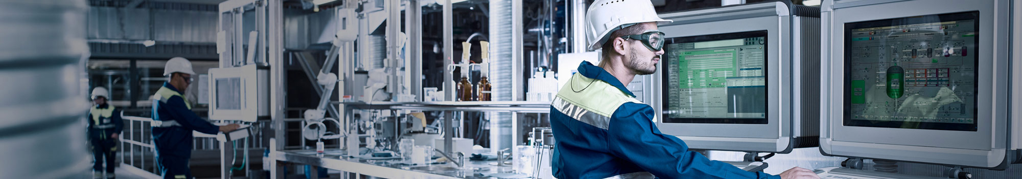 Factory worker in safety gear working at computers